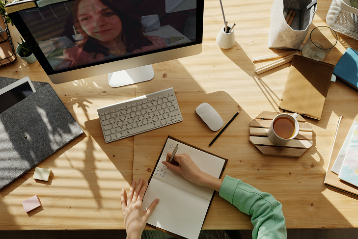 Plan sur un bureau d'un employé prenant des notes sur son pc